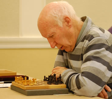 Visually Impaired player studies game on specially adapted  chessboard
