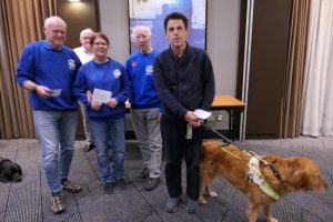 Tony Lawton (left), Gill Smith (second left) and John Osborne (right, with guide dog Vixen) receive their grading prizes from Bill Armstrong 